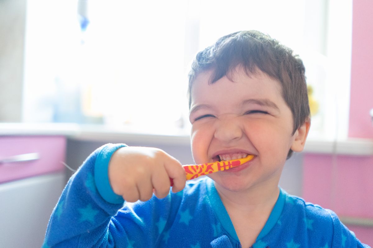 Parent helping a young child brush their teeth