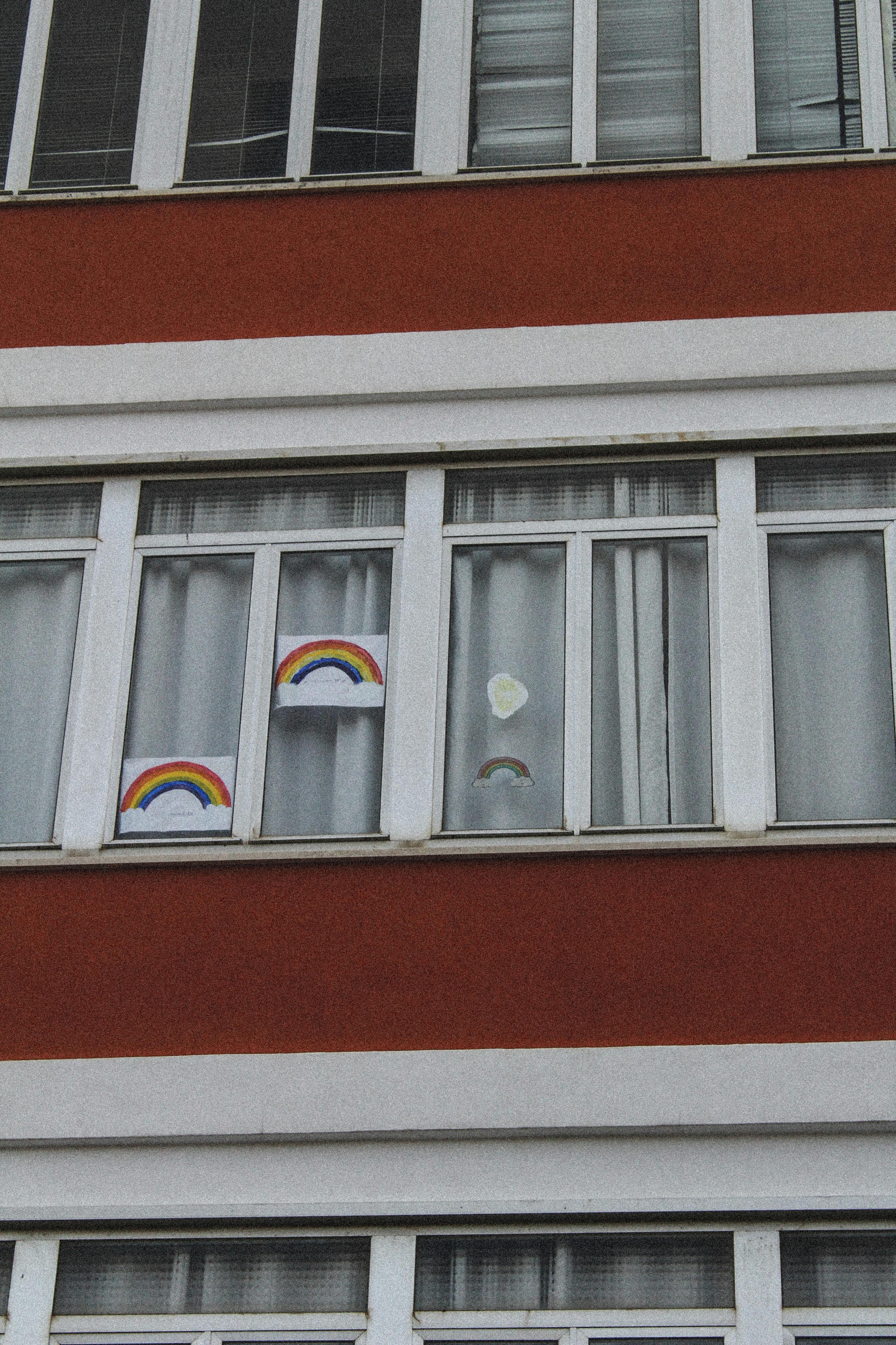公寓楼的窗户上装饰着充满活力的彩虹画，为城市风景增添了色彩