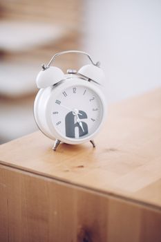 Stylish white analogue alarm clock on a wooden surface, perfect for minimalist design themes.