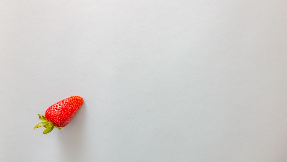 A single fresh strawberry on a white background, ideal for food and health themes.