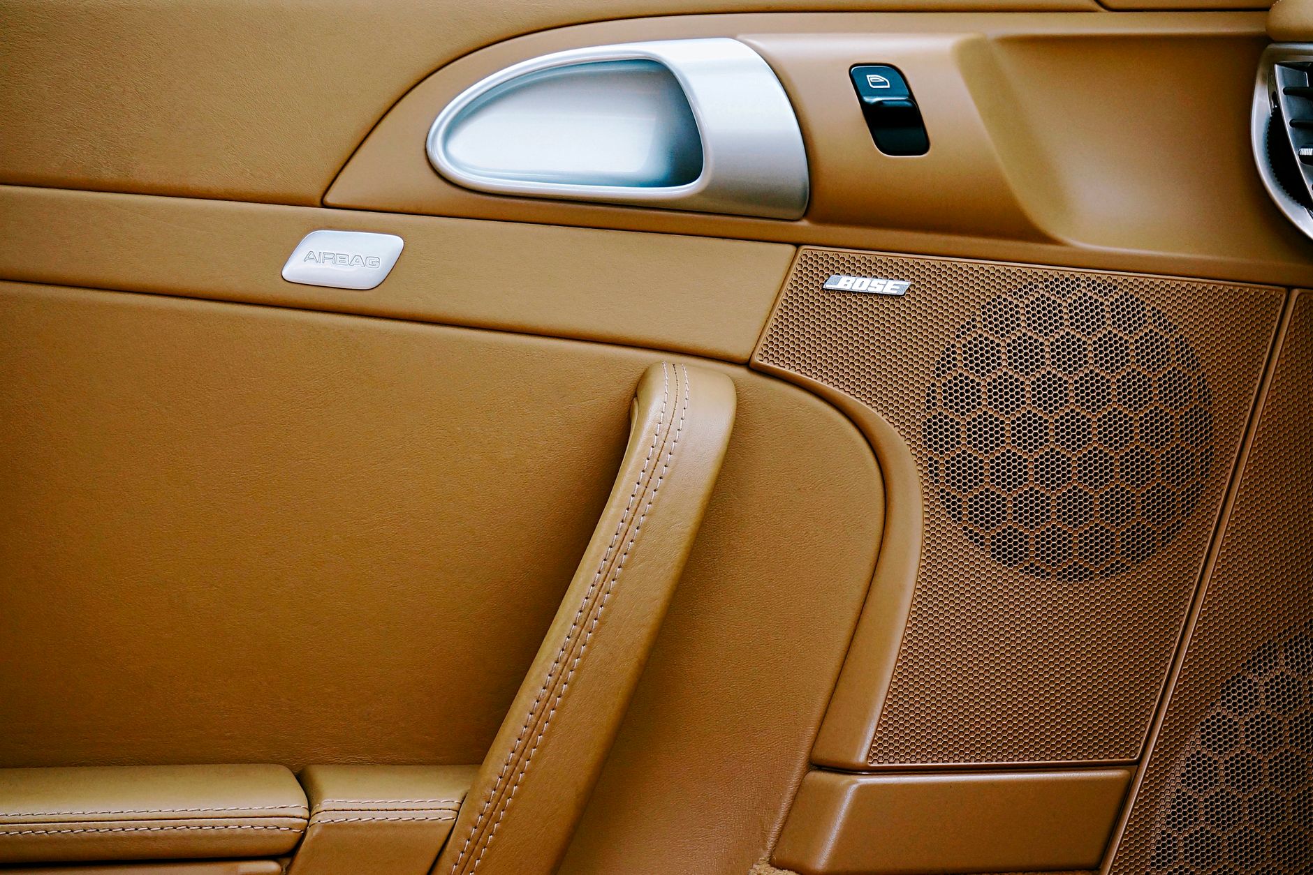 Close-up of a luxurious car interior featuring brown leather and a Bose speaker panel.