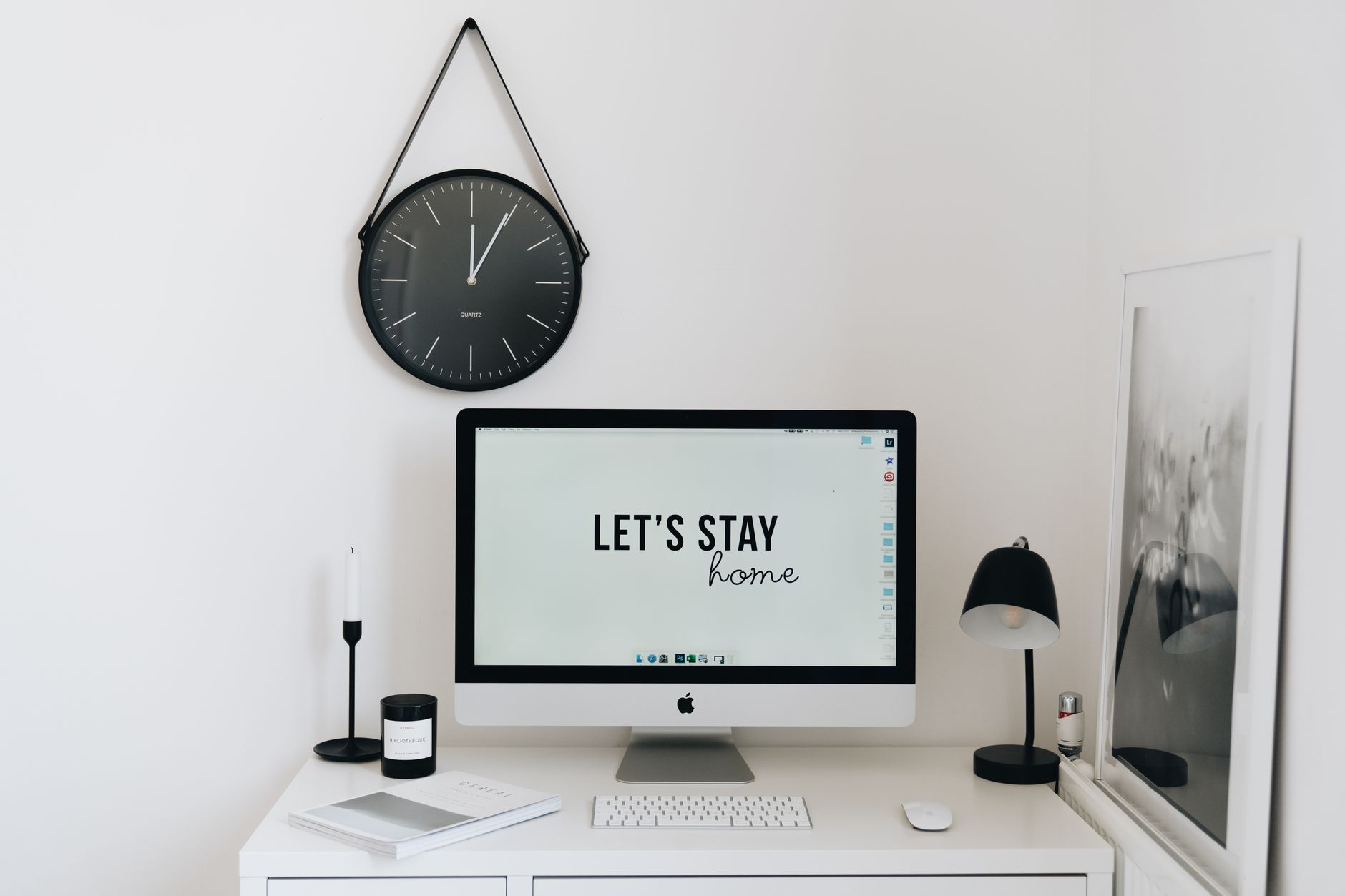 Stylish minimalist home office setup with modern computer, clock, and decor for a sleek workspace.