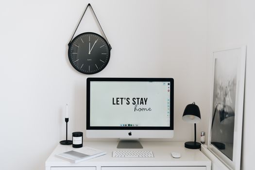 Stylish minimalist home office setup with modern computer, clock, and decor for a sleek workspace.