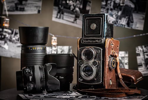 Retro film camera near contemporary photo lens on table