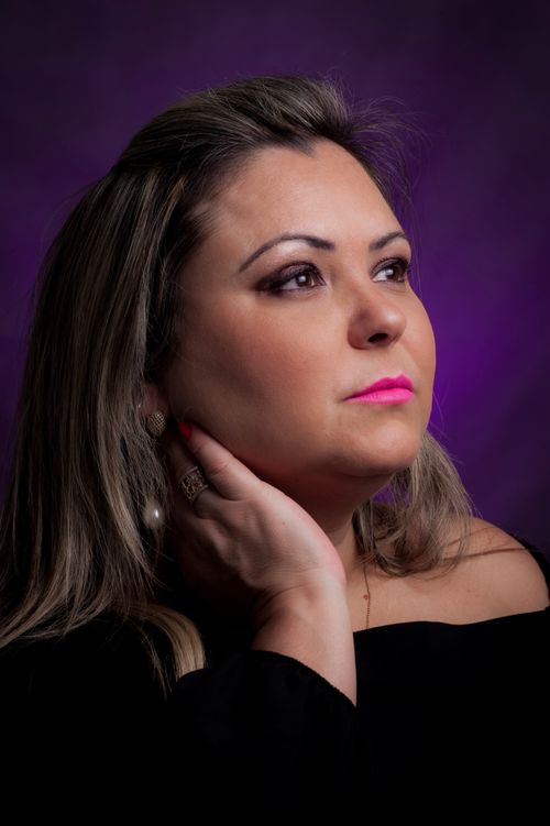 Free Pondering stylish female with pink lips in ring touching neck while looking away on violet background Stock Photo
