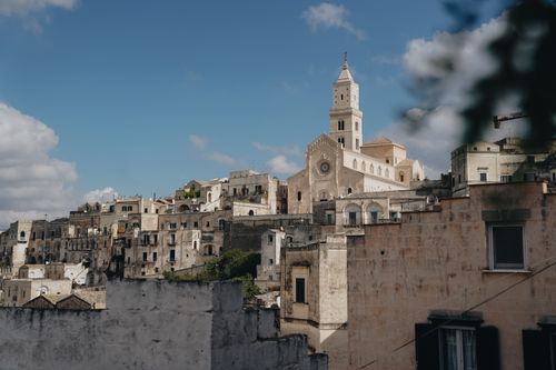 Free A picturesque old town in Italy with stone buildings and a prominent church under a clear blue sky. Stock Photo