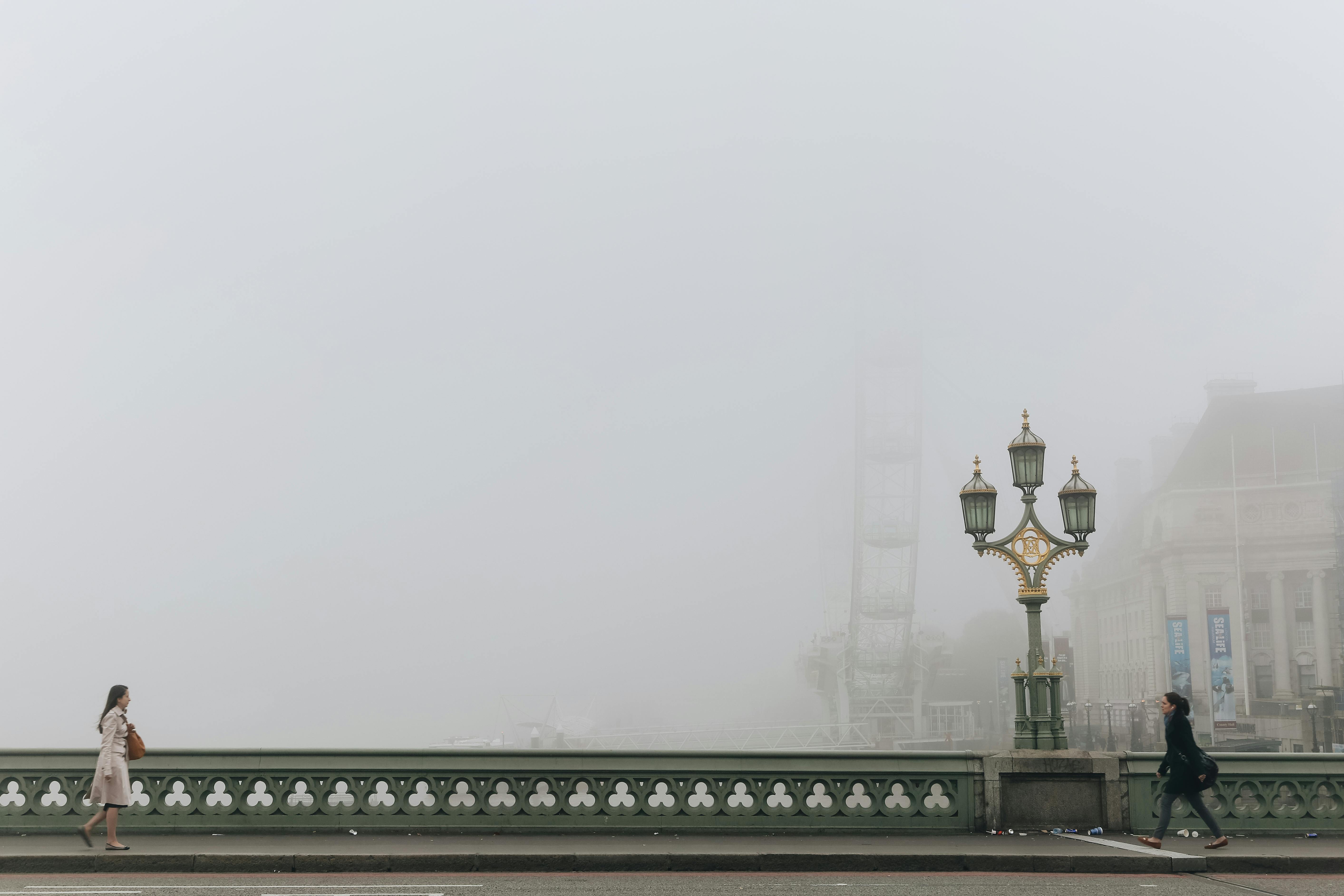 Misty morning view of Westminster Bridge with people walking in foggy London.