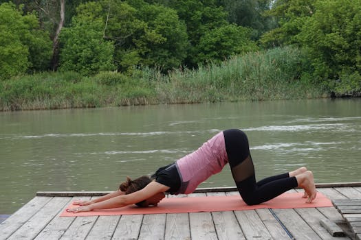 Woman practicing yoga outdoors by a serene river in Bratislava, focusing on flexibility and wellbeing.