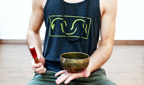 Man in Black Tank Top Holding Tibetan Singing Bowl 