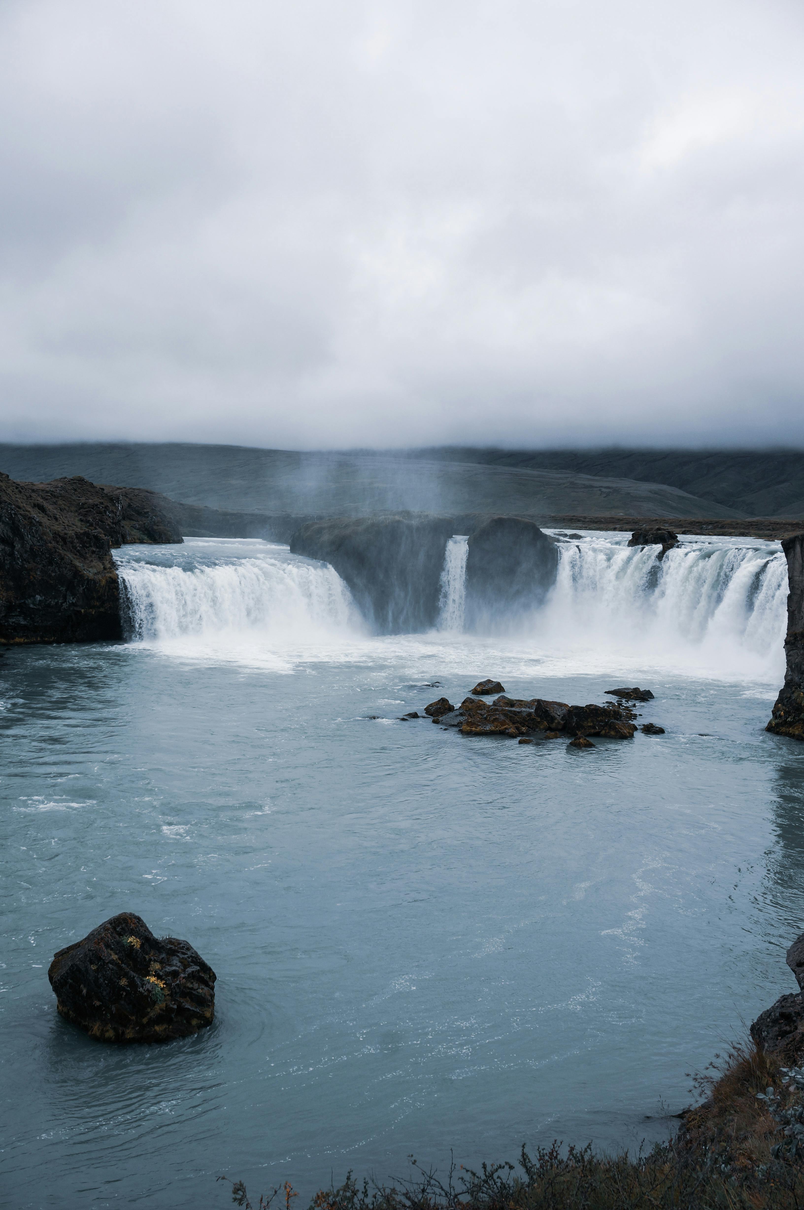 fast cascades in mountains near lake in overcast weather