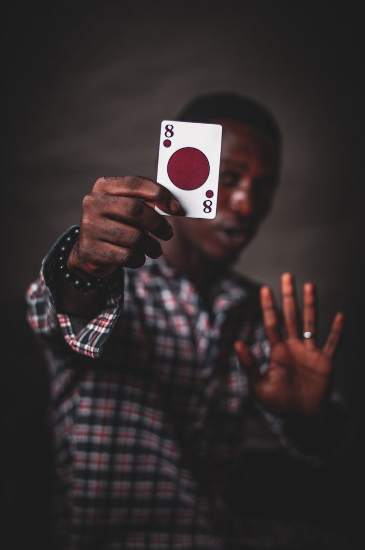 Black Man Showing Bright Playing Card On Gray Background