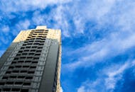 一座现代化的摩天大楼直插云霄，蓝天充满活力，云层散落