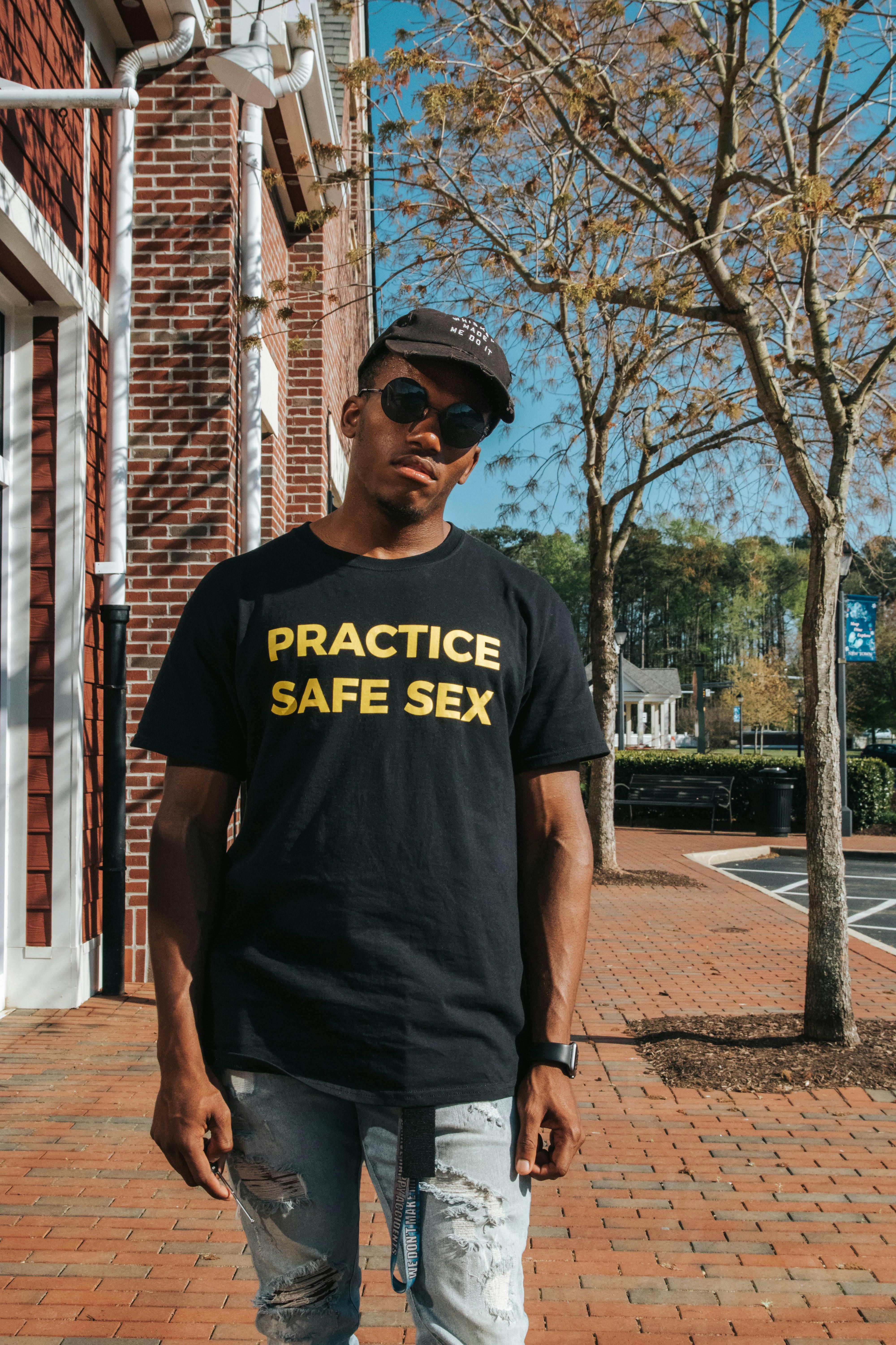 Trendy black man in sunglasses and cap walking on street · Free Stock Photo