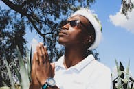 Stylish black man with prayer hands and sunglasses