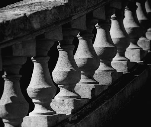 Black and white of aged masonry staircase with decorative balustrades and rough shabby handrails in daylight