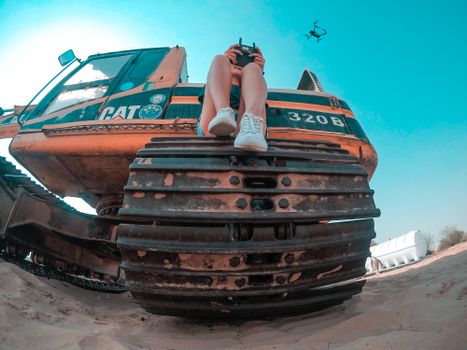 A woman controls a drone from a construction vehicle in Dubai's desert landscape.