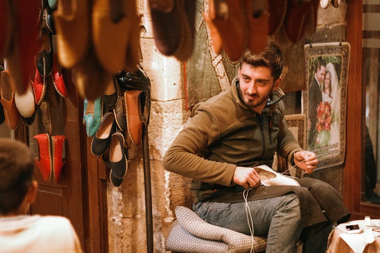Ethnic Bootmaker Sitting In Shoe Store