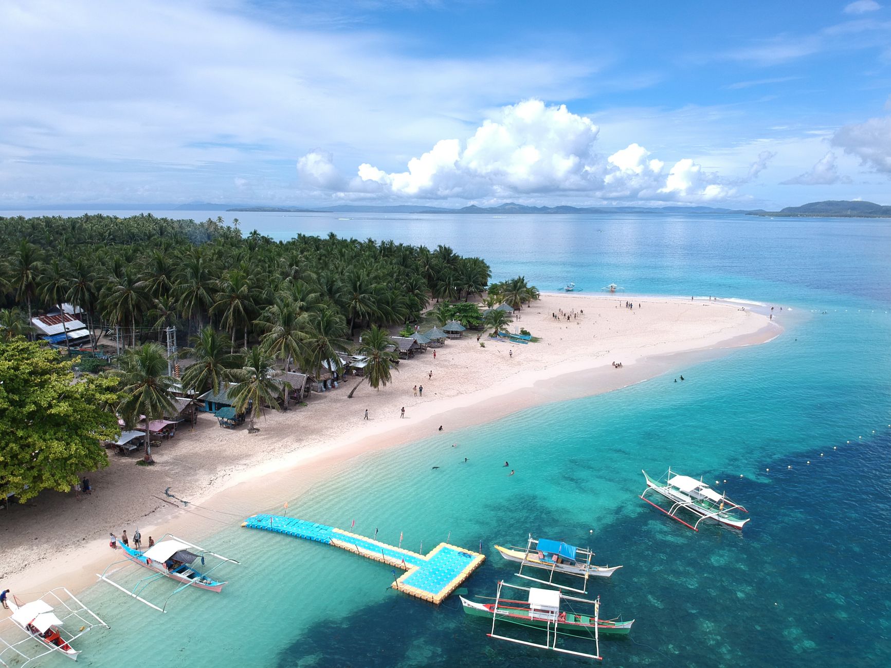 Aerial view of a stunning tropical beach in Caraga, Philippines, showcasing clear turquoise waters and lush surroundings.