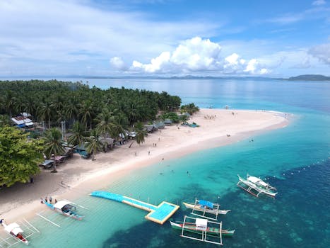 Aerial view of a stunning tropical beach in Caraga, Philippines, showcasing clear turquoise waters and lush surroundings.