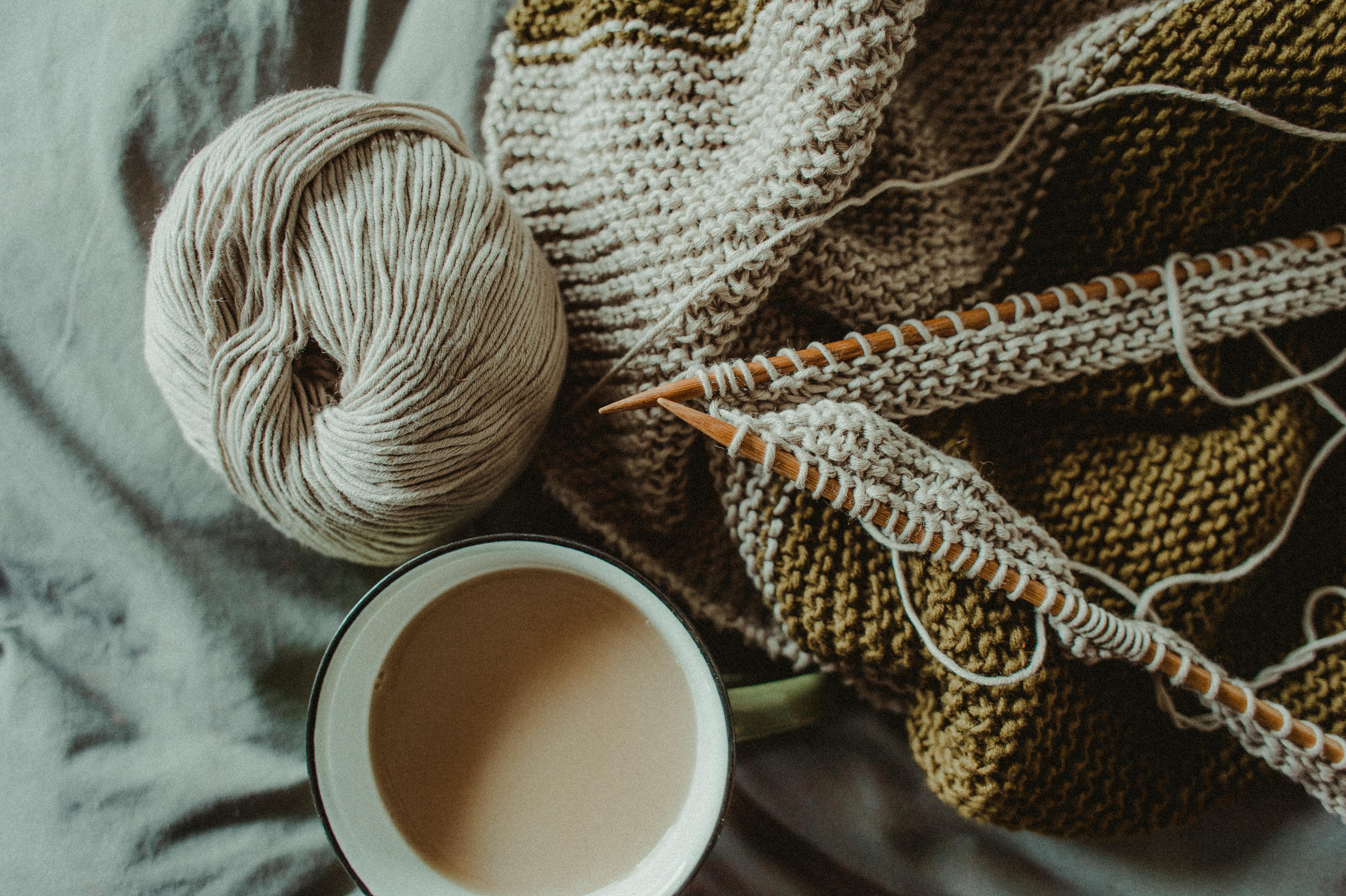 knitting supplies and cup of coffee placed on bed