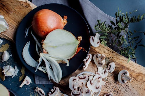 Chopped mushrooms and halved onion on table with herbs and spices