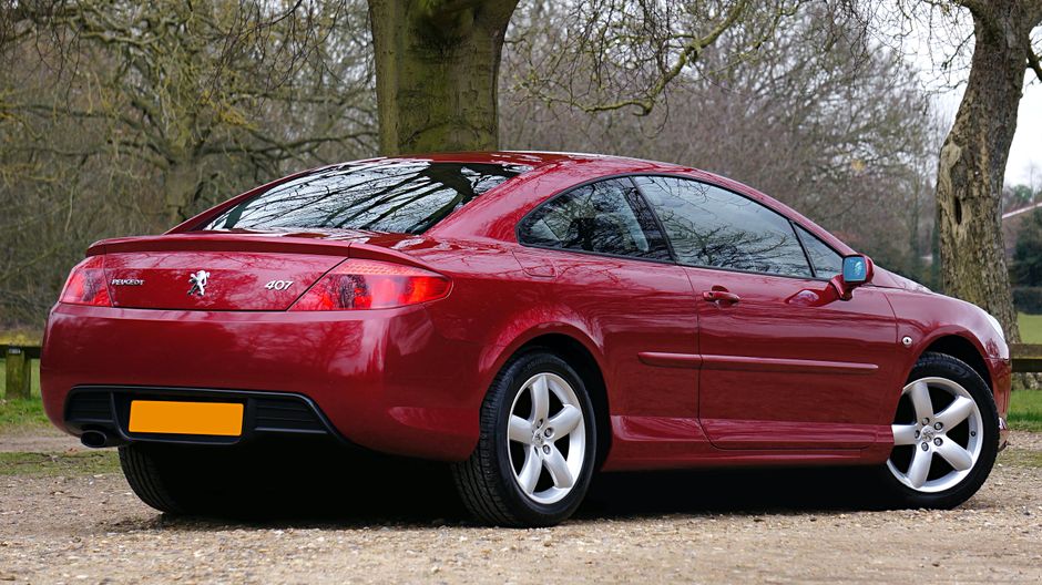 A sleek and luxurious red Peugeot 407 coupe parked outdoors.