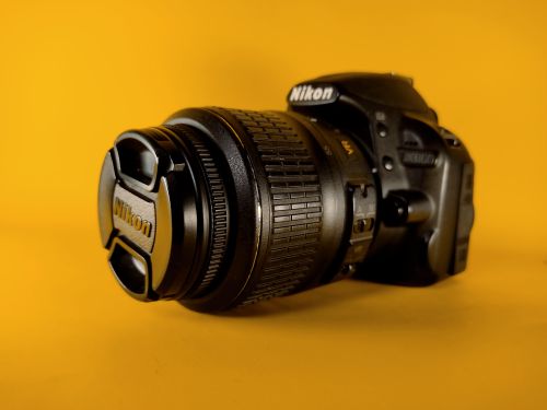 Free High-quality DSLR camera displayed against a vibrant yellow background, perfect for photography enthusiasts. Stock Photo