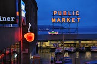 西雅图公共市场的夜间景观充满活力，霓虹咖啡和市场标志点亮了夜空