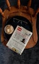 Newspaper and Coffee Drink on Black Tray in a Wooden Chair