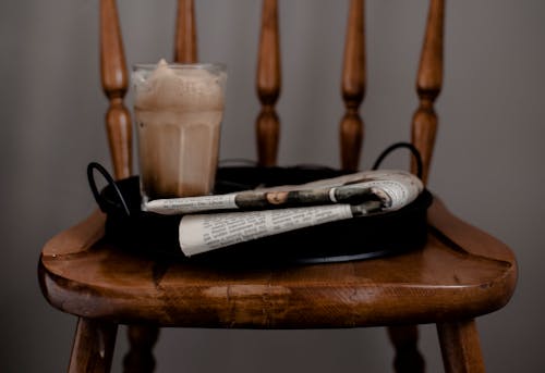 Free Foamy coffee and newspaper served on tray placed on chair Stock Photo