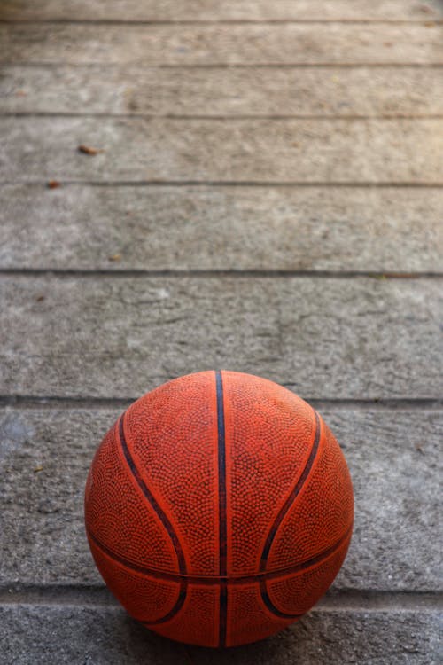 Free From above of orange basketball ball placed on ground on street on sunny day Stock Photo
