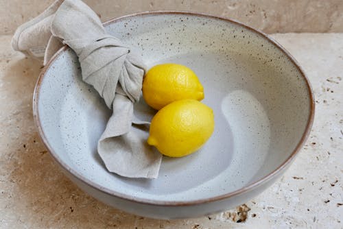 Healthy fresh lemons in bowl placed on table in kitchen