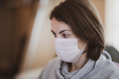 Free Close-up side view of a woman wearing a face mask indoors, embodying new normal health precautions. Stock Photo