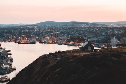 Light pink evening sky over bay among mountains on horizon and settlement on shoreline