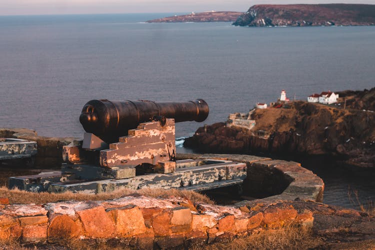 Black Gun On Support Against Ocean By Rocky Coast