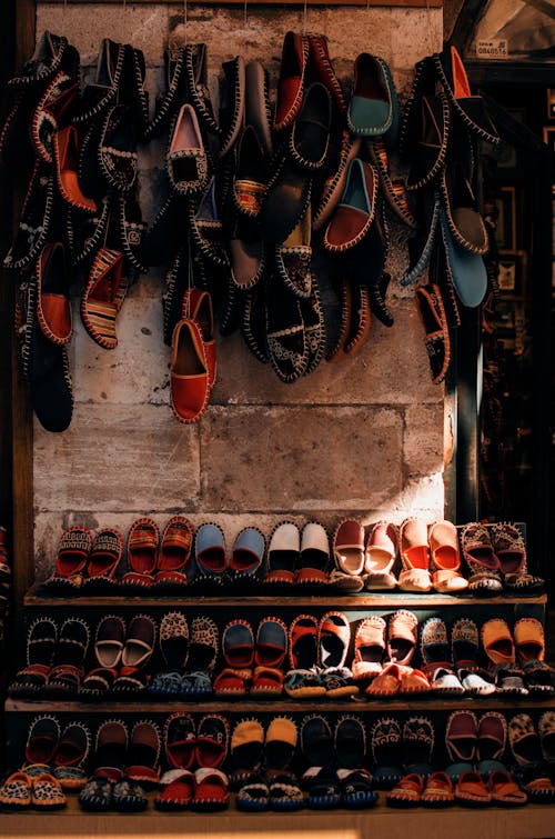 Colorful traditional shoes hanging on wall and placed on shelves