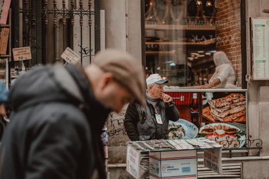 Senior male smoking while standing on street market and selling local souvenirs during work day