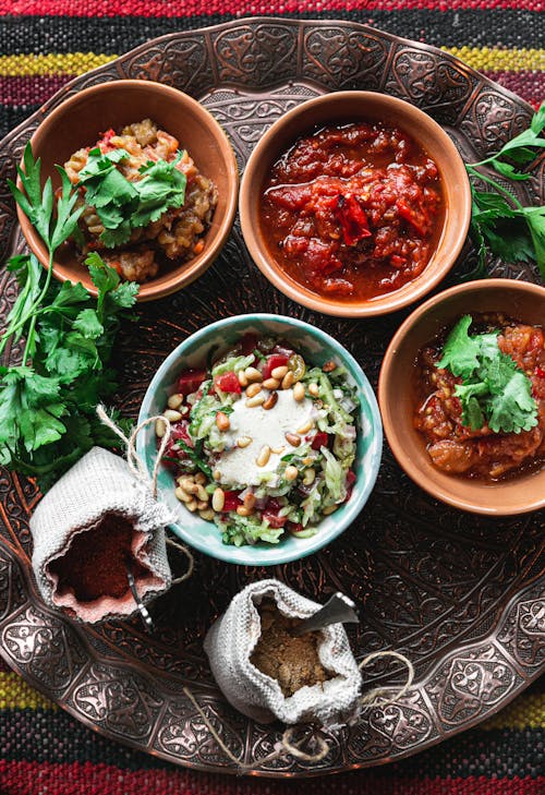 Bowls with healthy food and spices in linen bags served on copper tray