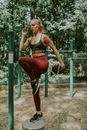 Full body of young slim female in sportswear doing knee lift exercise while warming up before training