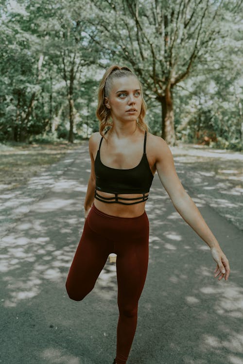 Стройная спортивная молодая женщина, растягивающая ногу во время тренировки