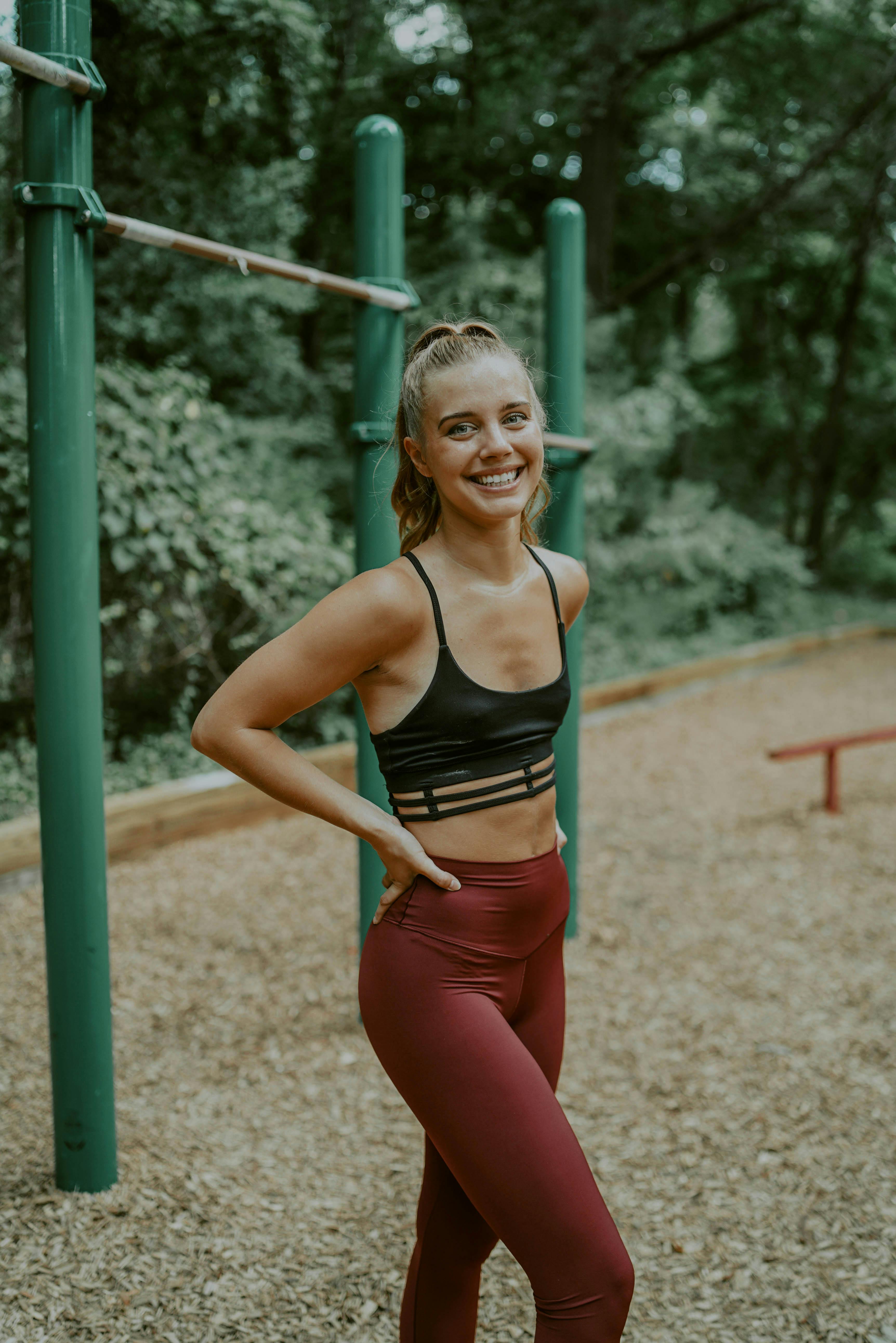 Athletic female in sports bra standing in park and stretching