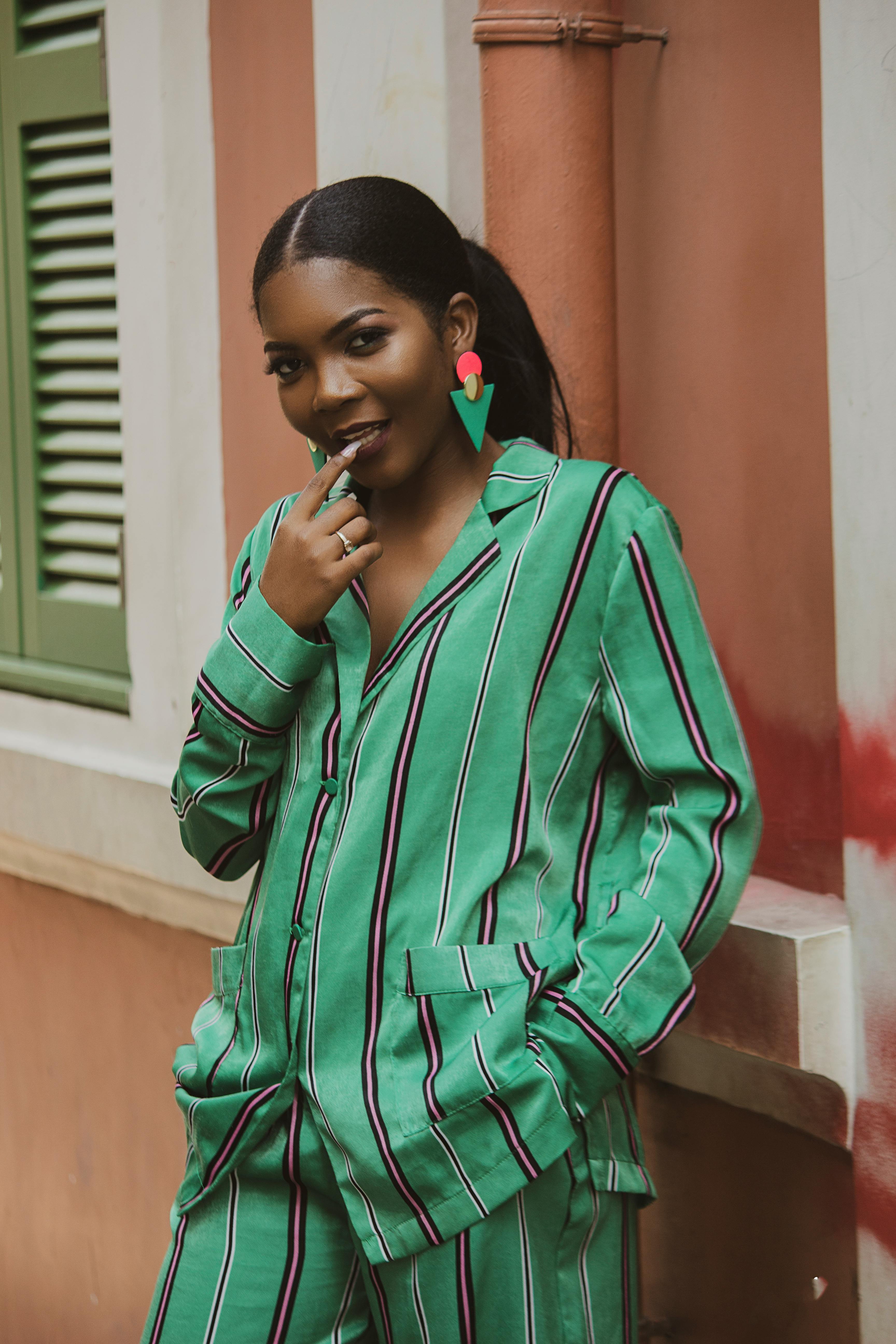 woman in teal and white striped zip up jacket standing near red concrete wall