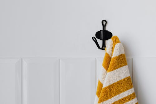Yellow and White Towel hanging on a Mounted Hook 