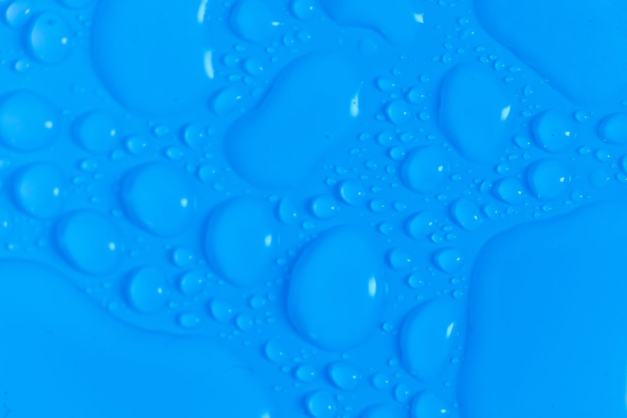 closeup top view of dark blue wet blurred background with still shiny