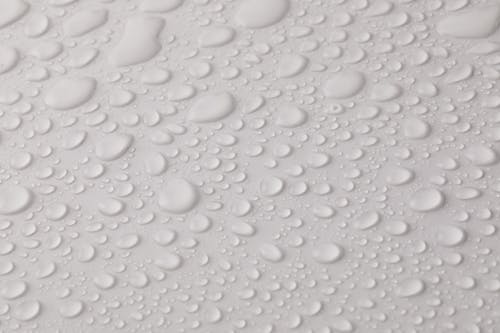 Free Closeup top view of plain wet abstract surface with small dripped water drops of different shapes placed on white background Stock Photo