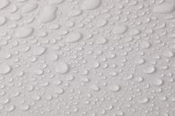 Closeup top view of plain wet abstract surface with small dripped water drops of different shapes placed on white background