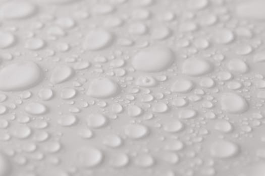 Detailed close-up of water droplets on a smooth, white surface, showcasing texture and clarity.
