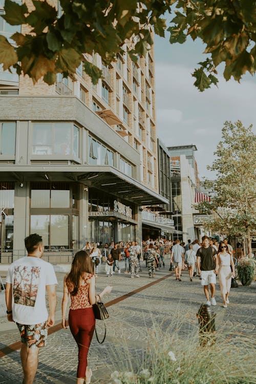 Free People walking on paved sidewalk near modern buildings and enjoying summer sunny day Stock Photo