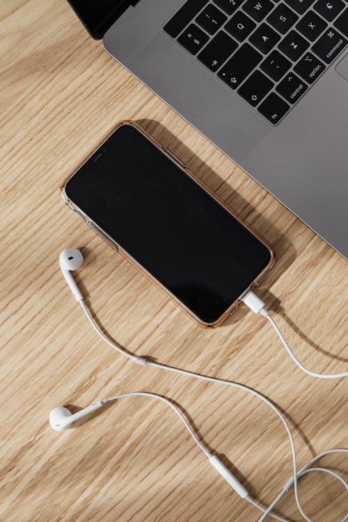 Composition of smartphone with earphones and laptop