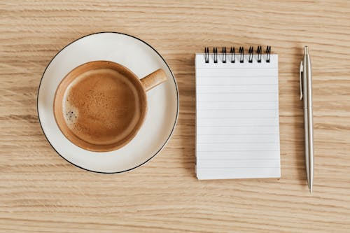 Free Composition of coffee and notebook with pen Stock Photo